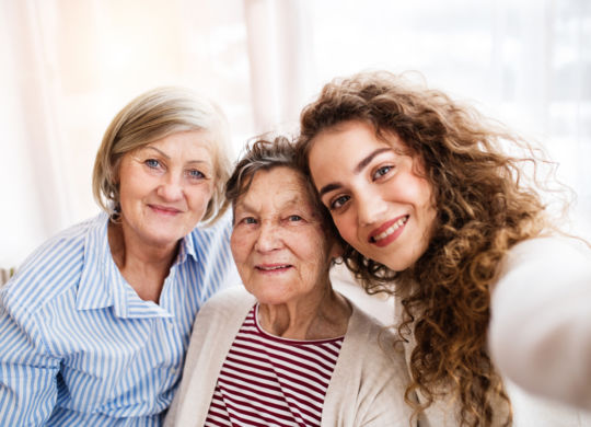 A teenage girl with her mother and grandmother at home. Family and generations concept.