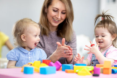 Woman teaches children modeling plasticine in day care center