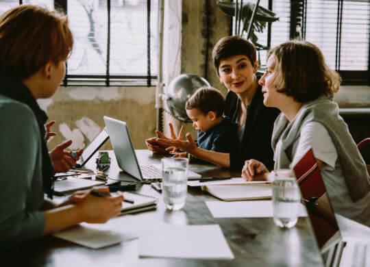 Young business women working together in creative coworking space. Successful mother with baby at work