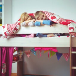 Two happy sibling children having fun in bunk bed under blanket
